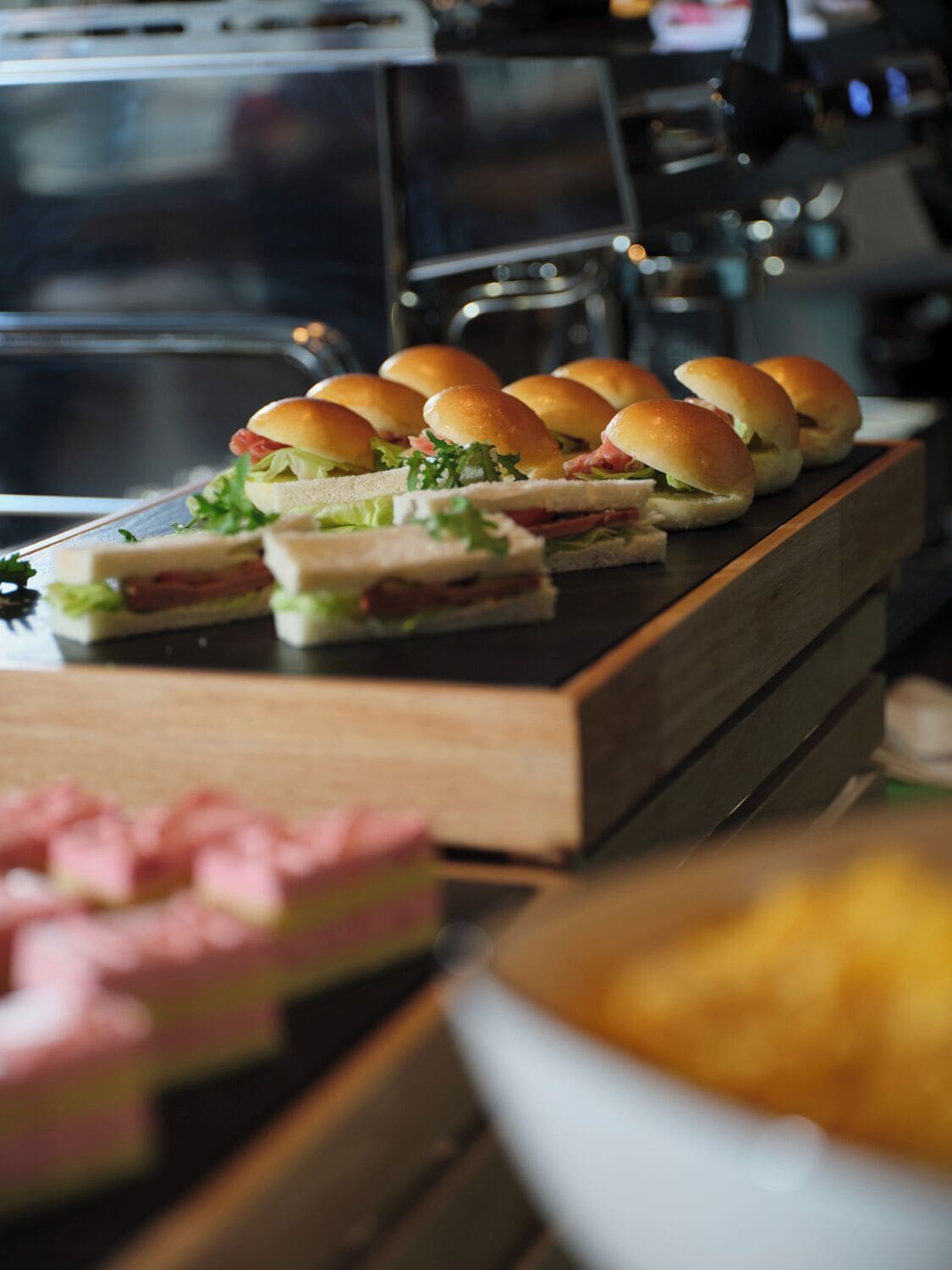 A buffet with sandwiches and a bowl of chips.