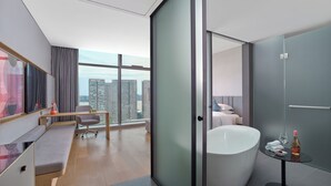 A modern hotel room with a large window, a sitting area with a desk, a large bathtub, and a small table with a bottle and glass. - Pagoda Hotel Hangzhou Binjiang (Hangzhou)