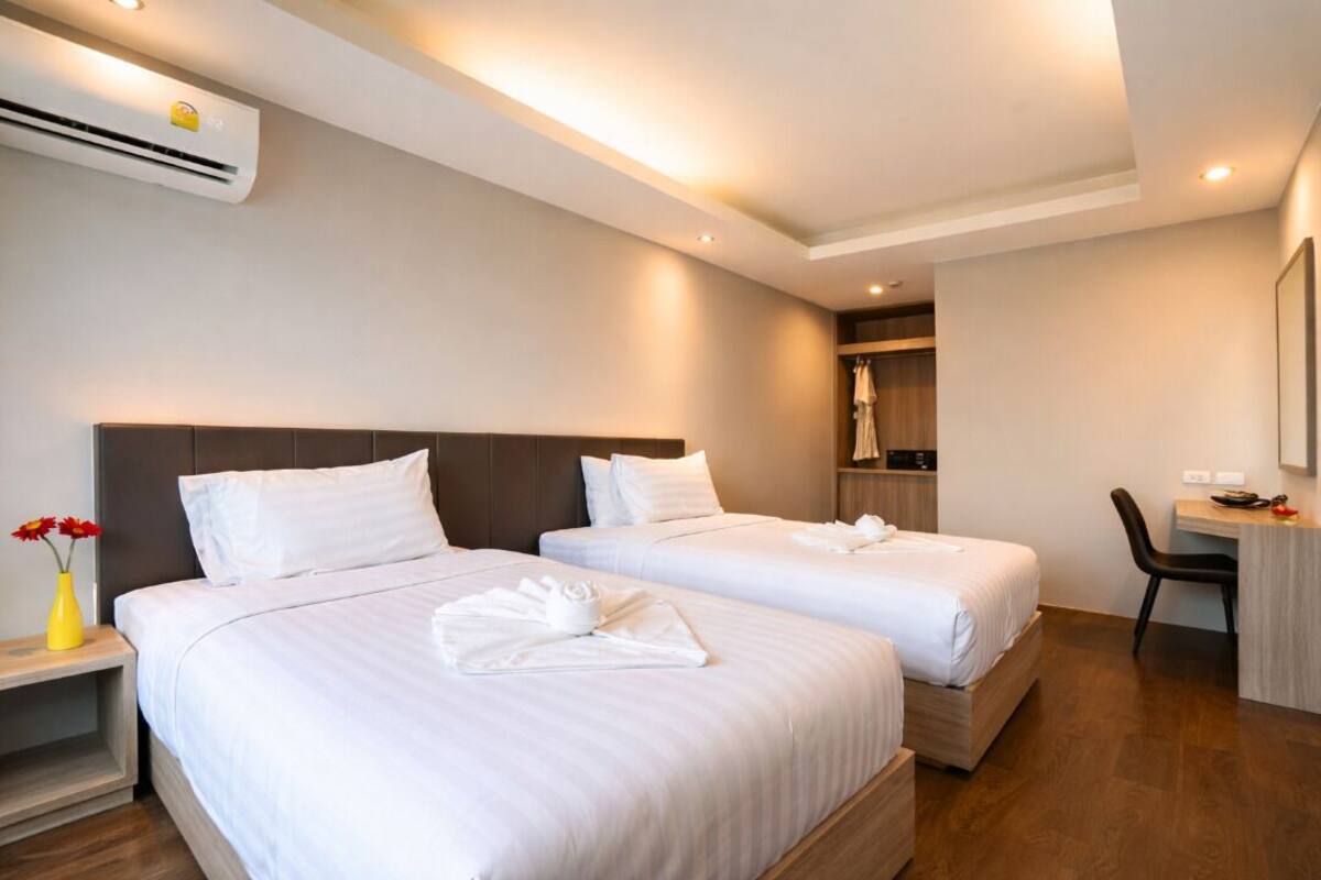 Een hotelkamer met twee bedden, een bureau, een stoel en een airconditioning.