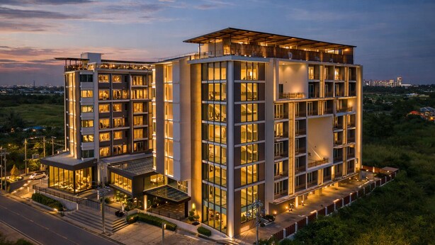 Un hôtel à plusieurs étages doté d’une architecture moderne, caractérisé par une façade en verre remarquable et une terrasse sur le toit.