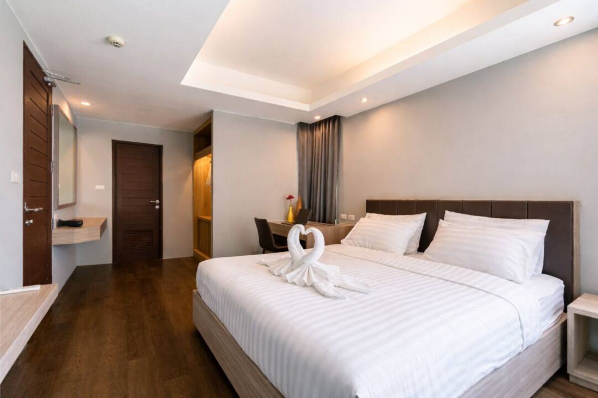 Een hotelkamer met een groot bed, een bureau, een stoel, een spiegel en een kledingkast.