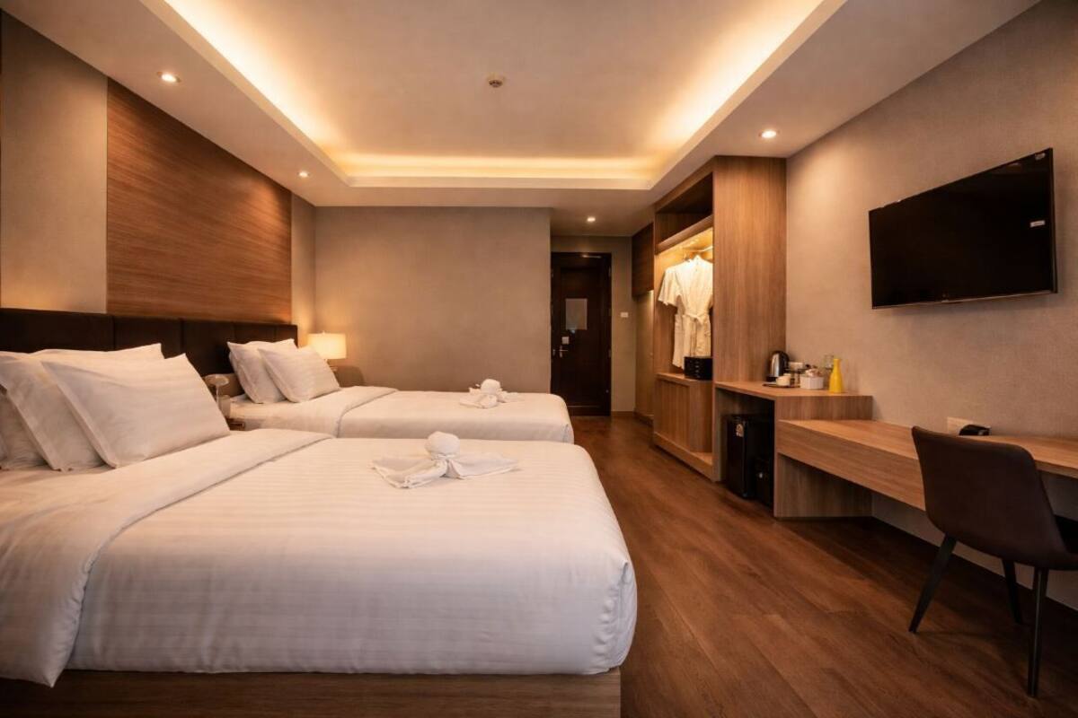 Een hotelkamer met twee bedden, een bureau, een televisie en een garderobe.