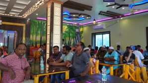 A restaurant with a modern interior, featuring a high ceiling with decorative lighting and a mural on the wall. - Sonajhuri Bagan Bari (Bolpur)