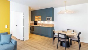 Un espacio habitable compacto con kitchenette, comedor y sofá.