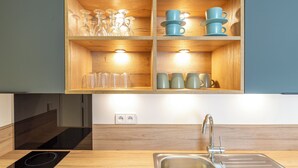 Una cocina moderna con armarios de madera, horno empotrado y pileta de acero inoxidable.