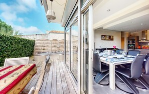 A modern outdoor dining area with a wooden deck, a hot tub, and a glass-enclosed kitchen. - Awesome home in Saint-Pierre-d'Oléron with WiFi (Saint-Pierre-d'Oléron)