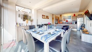 A modern dining area with a table set for four, a kitchen in the background, and a 'Welcome' sign on the door. - Awesome home in Saint-Pierre-d'Oléron with WiFi (Saint-Pierre-d'Oléron)
