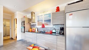 A modern kitchen with a stainless steel refrigerator, a microwave, and a coffee maker. There is a window with a beach view and a red towel hanging on the door. - Awesome home in Saint-Pierre-d'Oléron with WiFi (Saint-Pierre-d'Oléron)