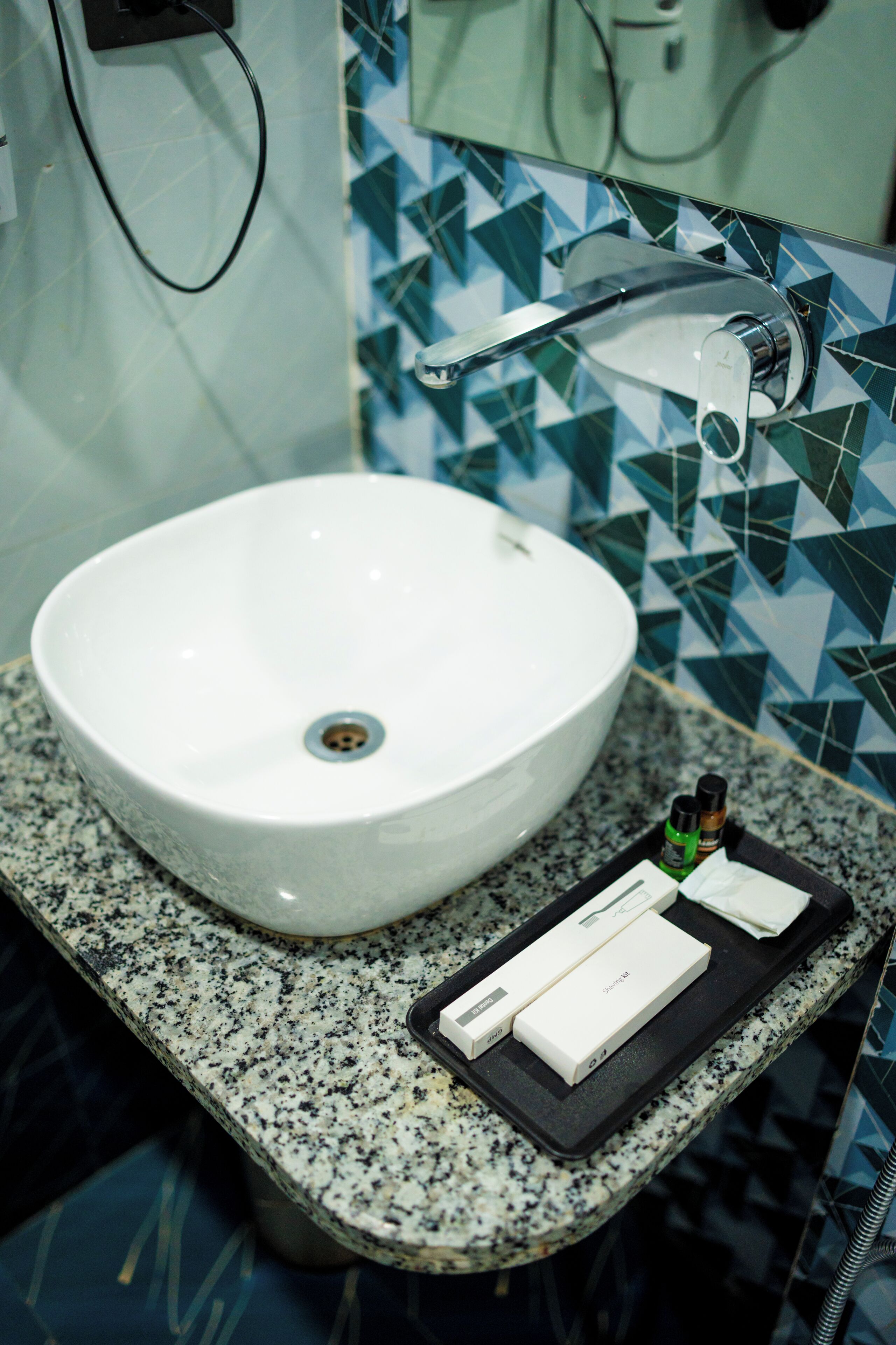 Un baño con lavamanos blanco, espejo y salpicadero de azulejos.