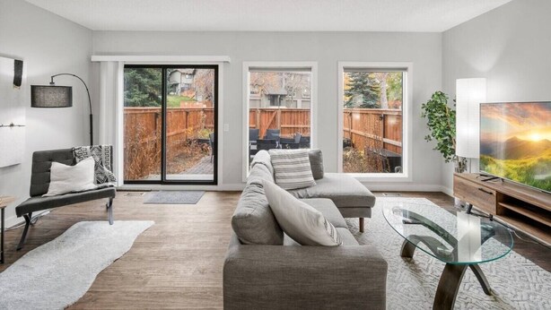A modern living room with a sofa, a glass coffee table, and a TV.