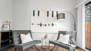 A modern living room with a grey sofa set, a small side table, a floor lamp, and a large abstract wall art piece.