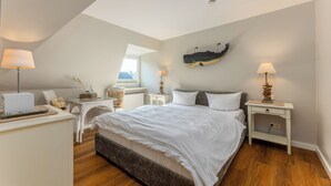 A bedroom with a bed, bedside tables, a desk, and a lamp. - Sylt Rooms 7 - Sag Harbour - Westerland (Westerland)