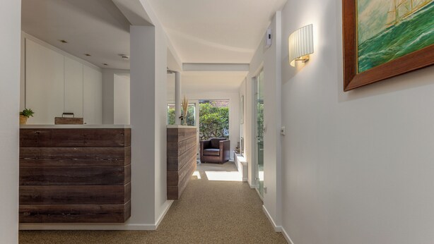 A hallway with a wooden bench, a wall-mounted light fixture, and a framed painting. - Sylt Rooms 10 - Shelter Island - Westerland (Westerland)