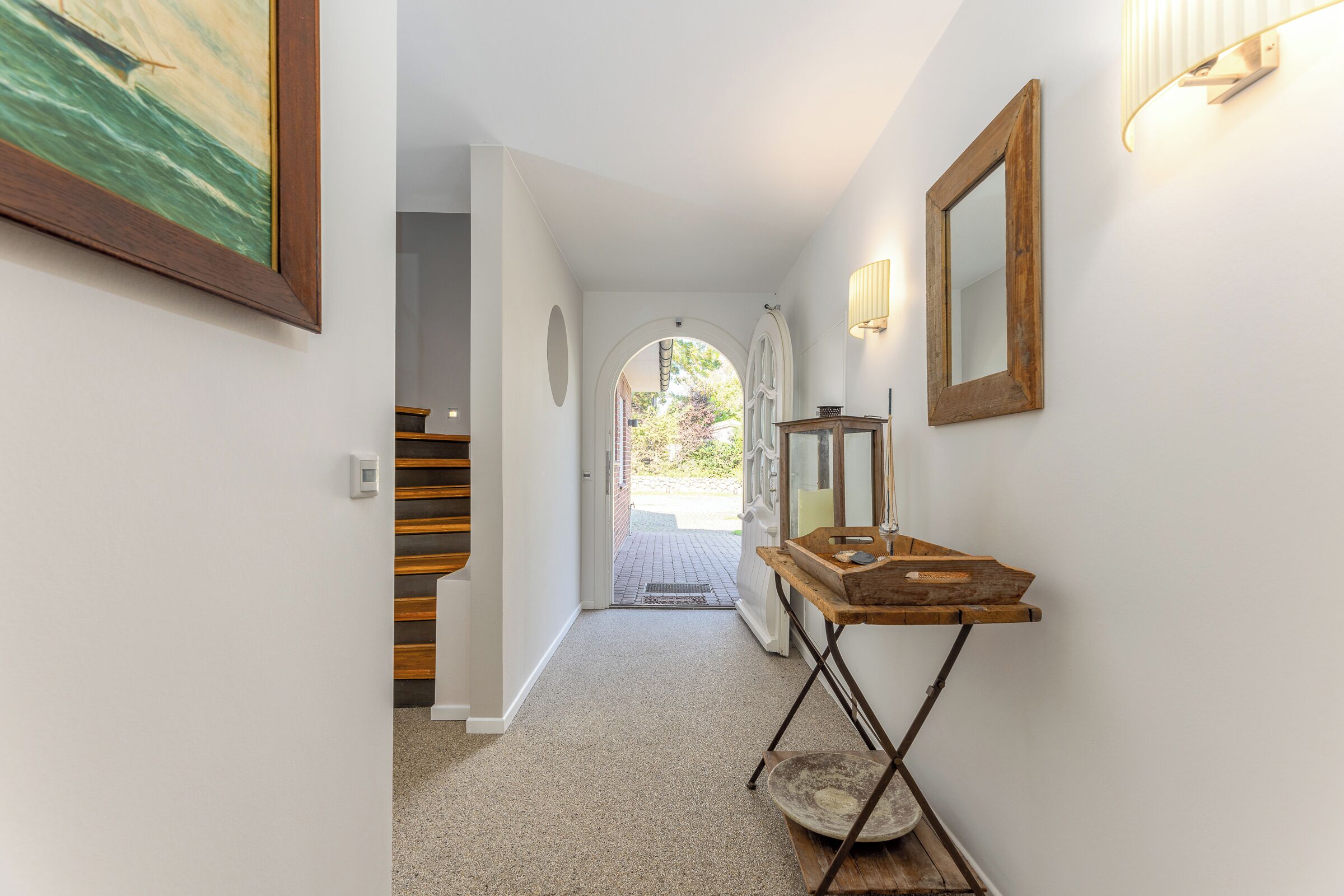 Un pasillo con una mesa de madera, un espejo y un cuadro en la pared.