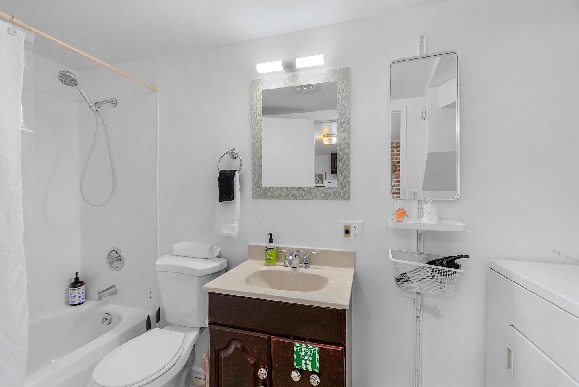 A modern bathroom with a shower, toilet, sink, and a first aid kit sign.