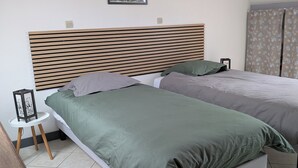 A bedroom with two beds, a wooden headboard, a framed picture on the wall, and a small table with a picture frame.