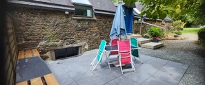 A stone building with a tiled patio, outdoor furniture, and a garden area.
