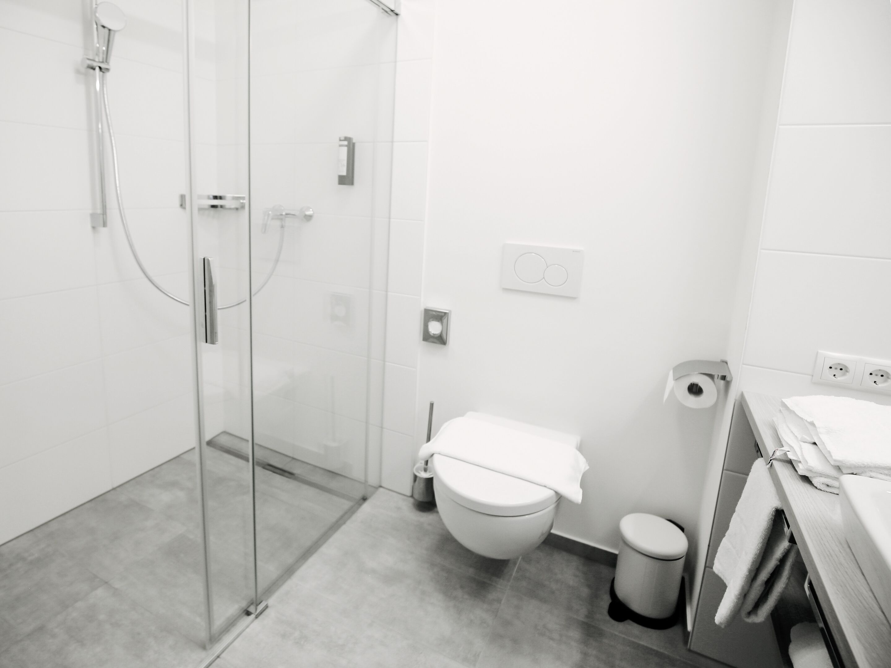 Un baño moderno con cabina de ducha de vidrio, inodoro y zona de lavabo con perchero.