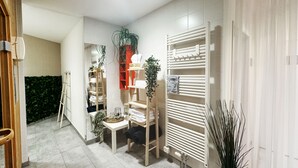 Ein modernes Badezimmer mit weißen Fliesen, einem Heizkörper, einem Handtuchhalter und einem Ablagebereich mit Pflegeprodukten.
