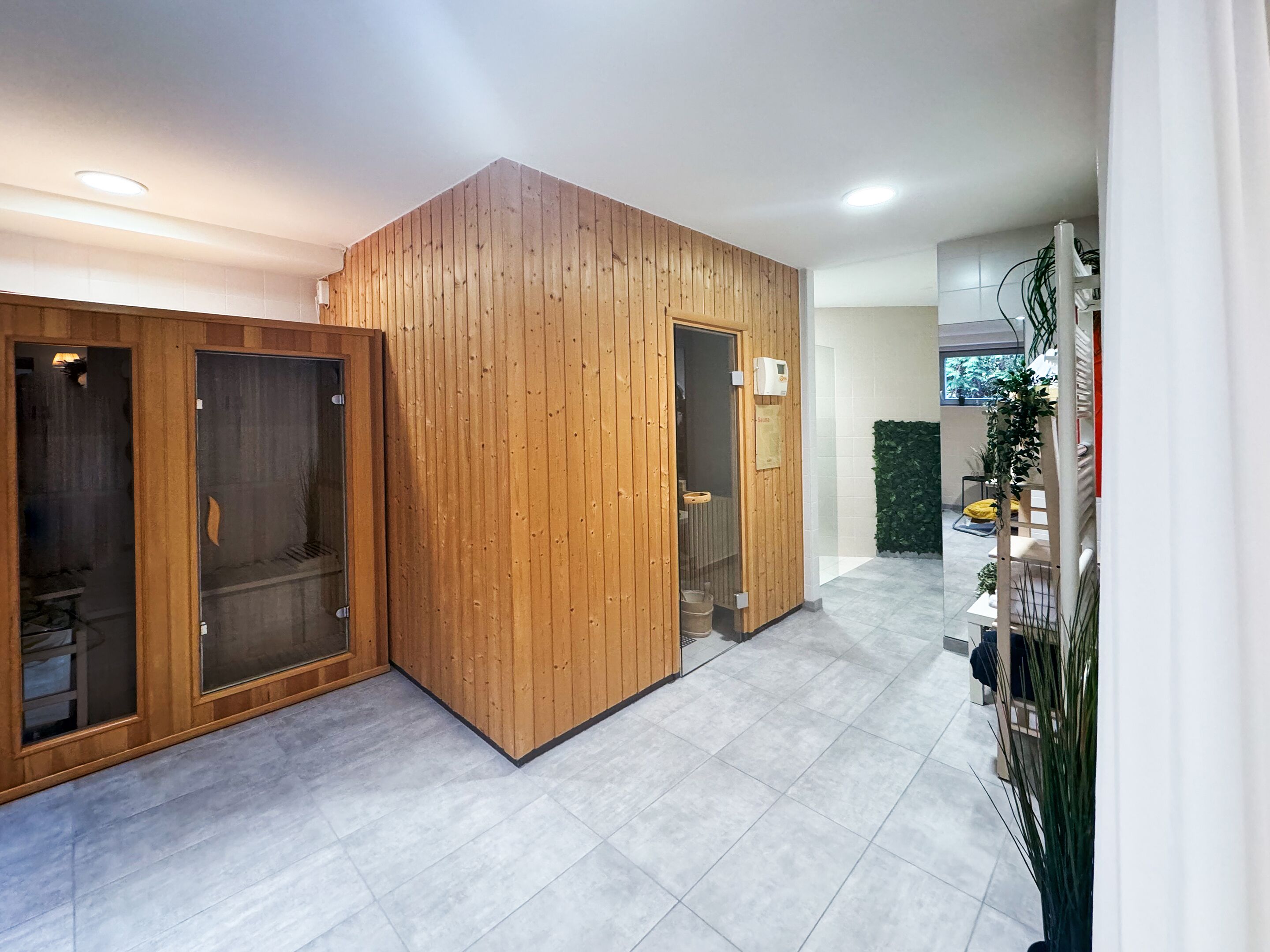 Un moderno vestíbulo de hotel con mostrador de recepción de madera, un panel de vidrio y suelo de baldosas.
