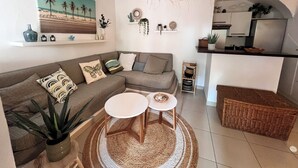 A living room with a sofa, two side tables, a hanging light fixture, and a kitchen area with a counter and cabinets. - Mini Villa U Campa Be - 5 people 250 m from the beach San Cyprianu Corsica (lecci)