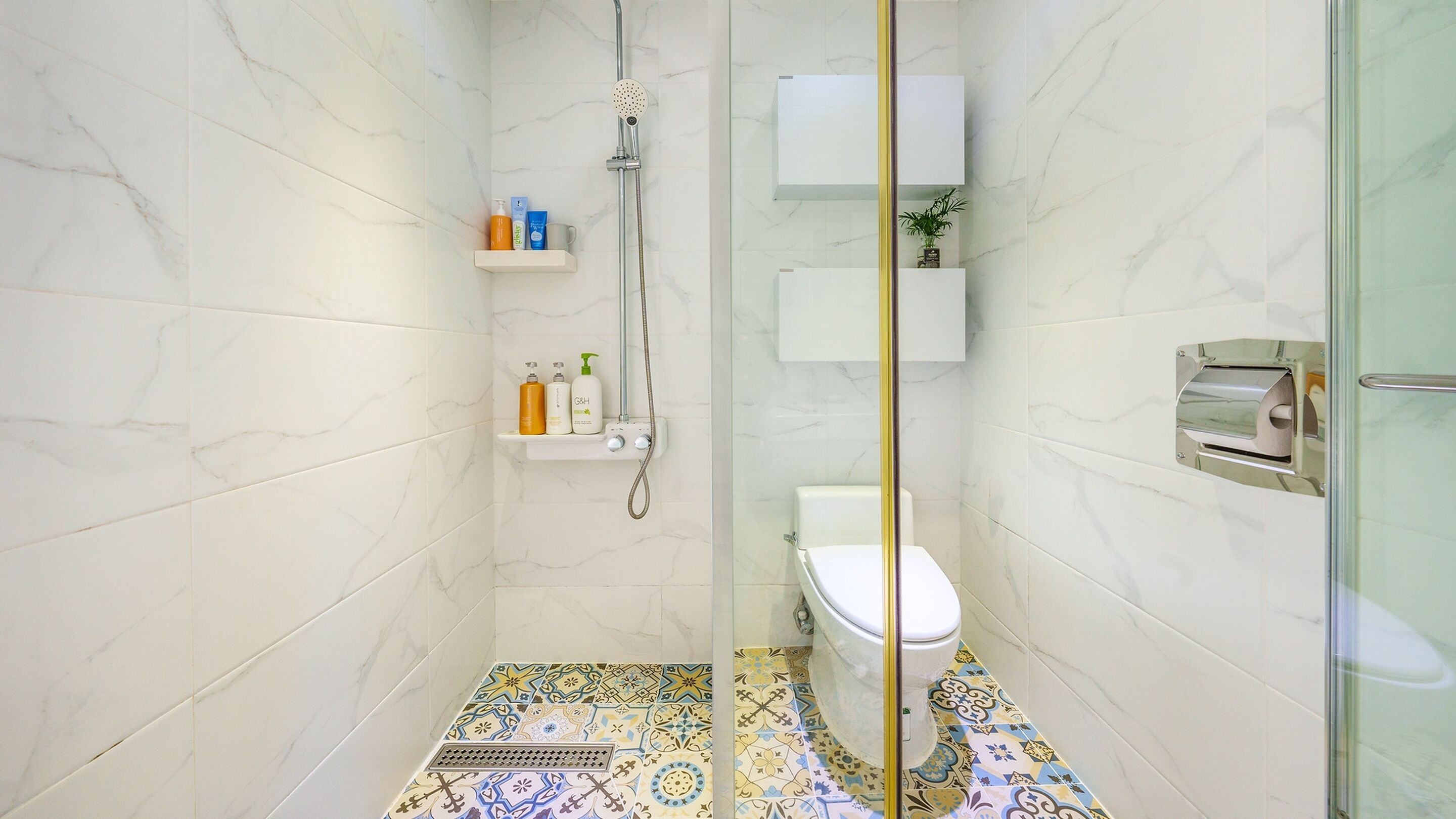 A modern bathroom with a glass shower enclosure, a toilet, and a sink.