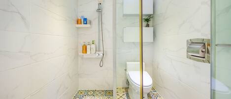 A modern bathroom with a glass shower enclosure, a toilet, and a sink.