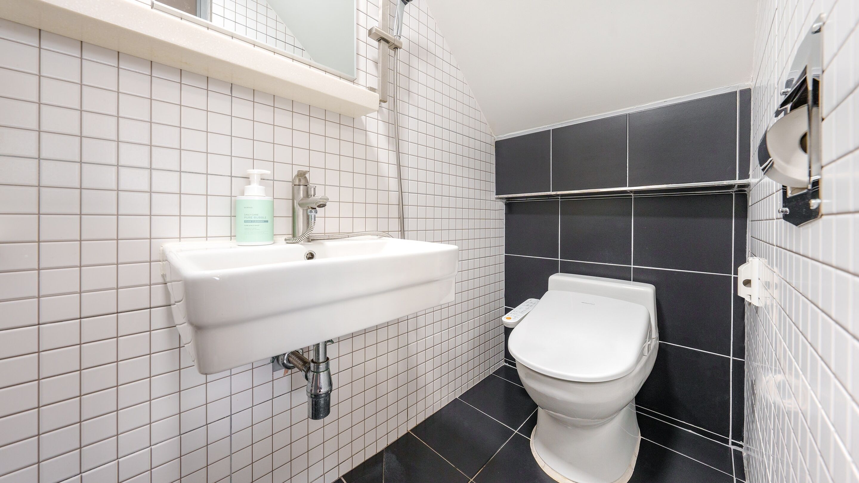 Un baño con lavamanos blanco, inodoro y zona de ducha.
