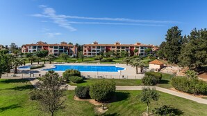 A hotel with a large swimming pool, multiple buildings with red roofs, and surrounding greenery. - El Rincon del Golf III - Isla Canela Golf GRHIII6P6 (Isla Canela)