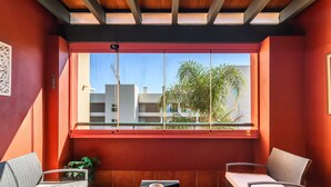 A balcony with two wicker chairs, a small table, and a view of buildings and trees. - El Rincon del Golf III - Isla Canela Golf GRHIII6P6 (Isla Canela)