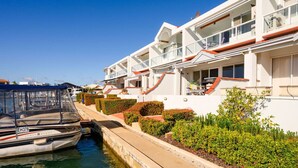 A white building with balconies, a canal, and a boat docked in front.