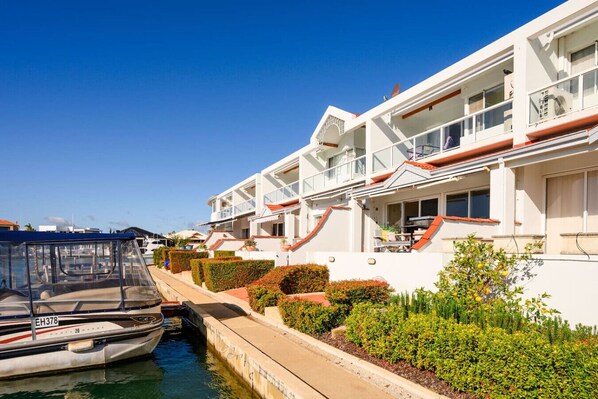 A white building with balconies, a canal, and a boat docked in front. - On the Canal in Halls Head (Halls Head)