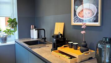 Ett modernt kök med en inbyggd diskho, en kaffemaskin och ett träbricka.