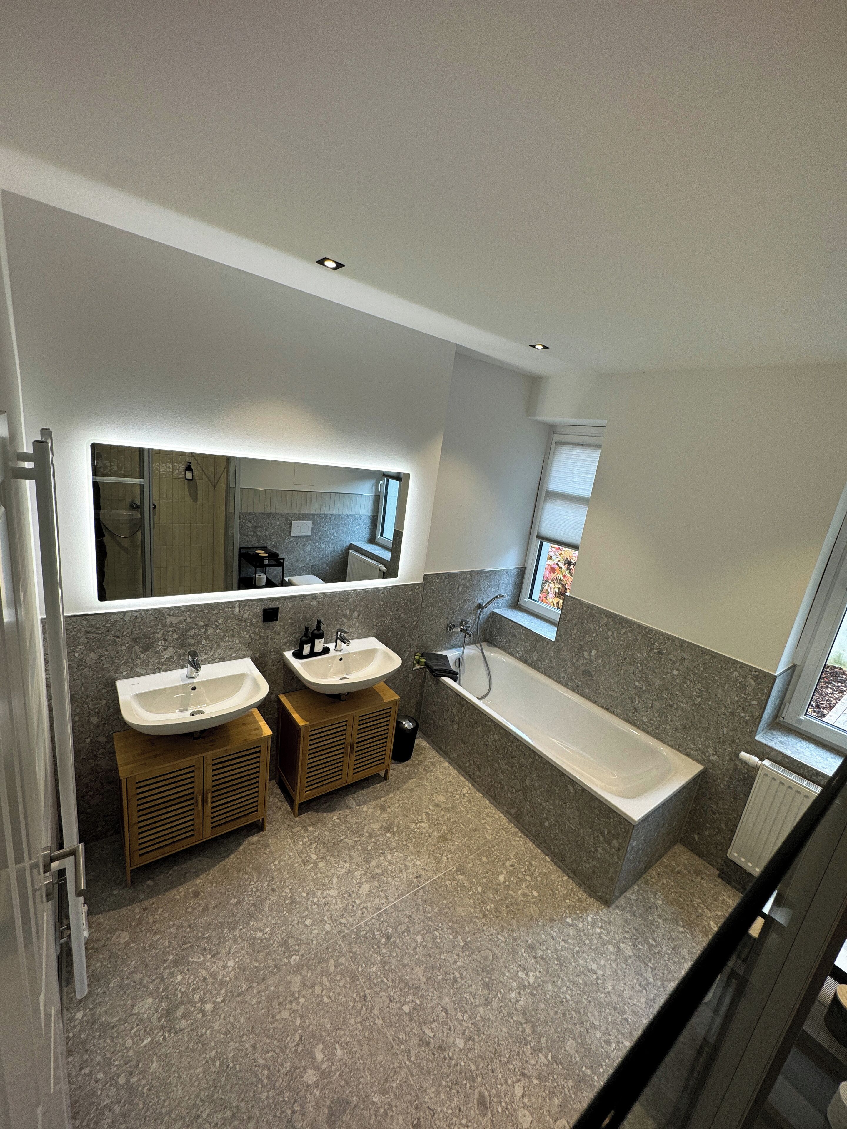 Une salle de bain moderne avec deux lavabos, une baignoire et un grand miroir.