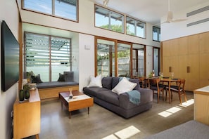A modern living room with a sofa, coffee table, and dining area.
