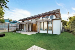 A modern house with a covered patio, a well-maintained lawn, and a fenced backyard.
