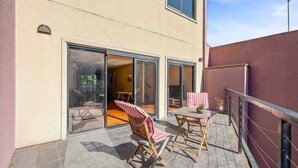 A modern building with a glass door entrance, a patio with a table and chairs, and a view of the interior. - Comfy 3-bedroom building in St Kilda with fitness room, WiFi (Saint Kilda)