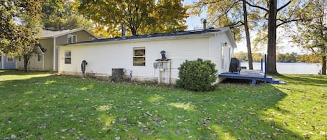 A single-story mobile home with a small porch, a chimney, and a water feature.