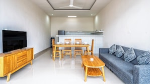 A modern living room with a wooden dining table, sofa, and TV stand. - Aruna Villa 2 by Betterplace (Canggu)