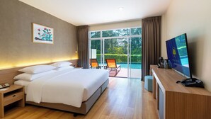 Une chambre d’hôtel équipée d’un lit, d’un bureau, d’une télévision et offrant une vue sur une piscine et un espace verdoyant.
