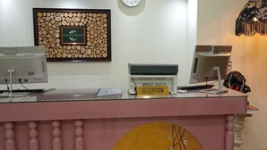 Un comptoir d’accueil avec un logo encadré, une enseigne indiquant « Réception » et un écran d’ordinateur.