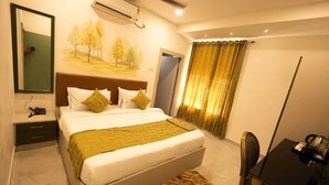 Une chambre d’hôtel avec un lit, une table de chevet, un bureau et une chaise.