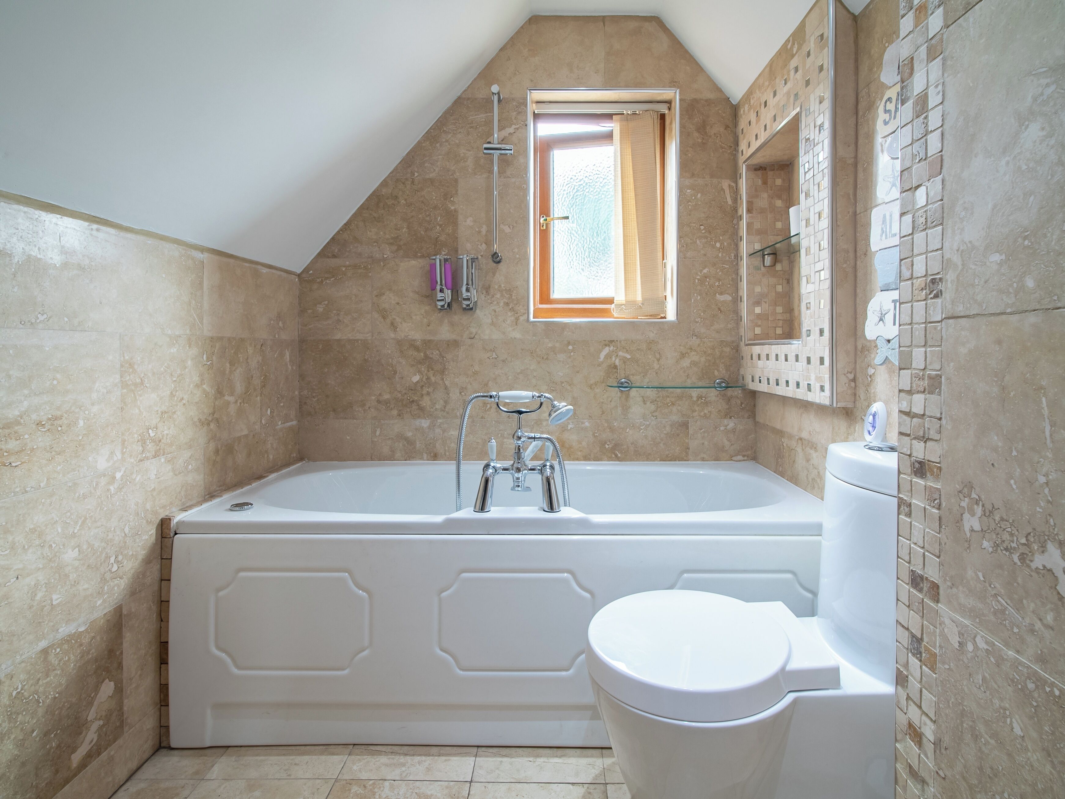 A bathroom with a large bathtub, a toilet, and a shower. There is a window above the bathtub and a mirror on the wall.