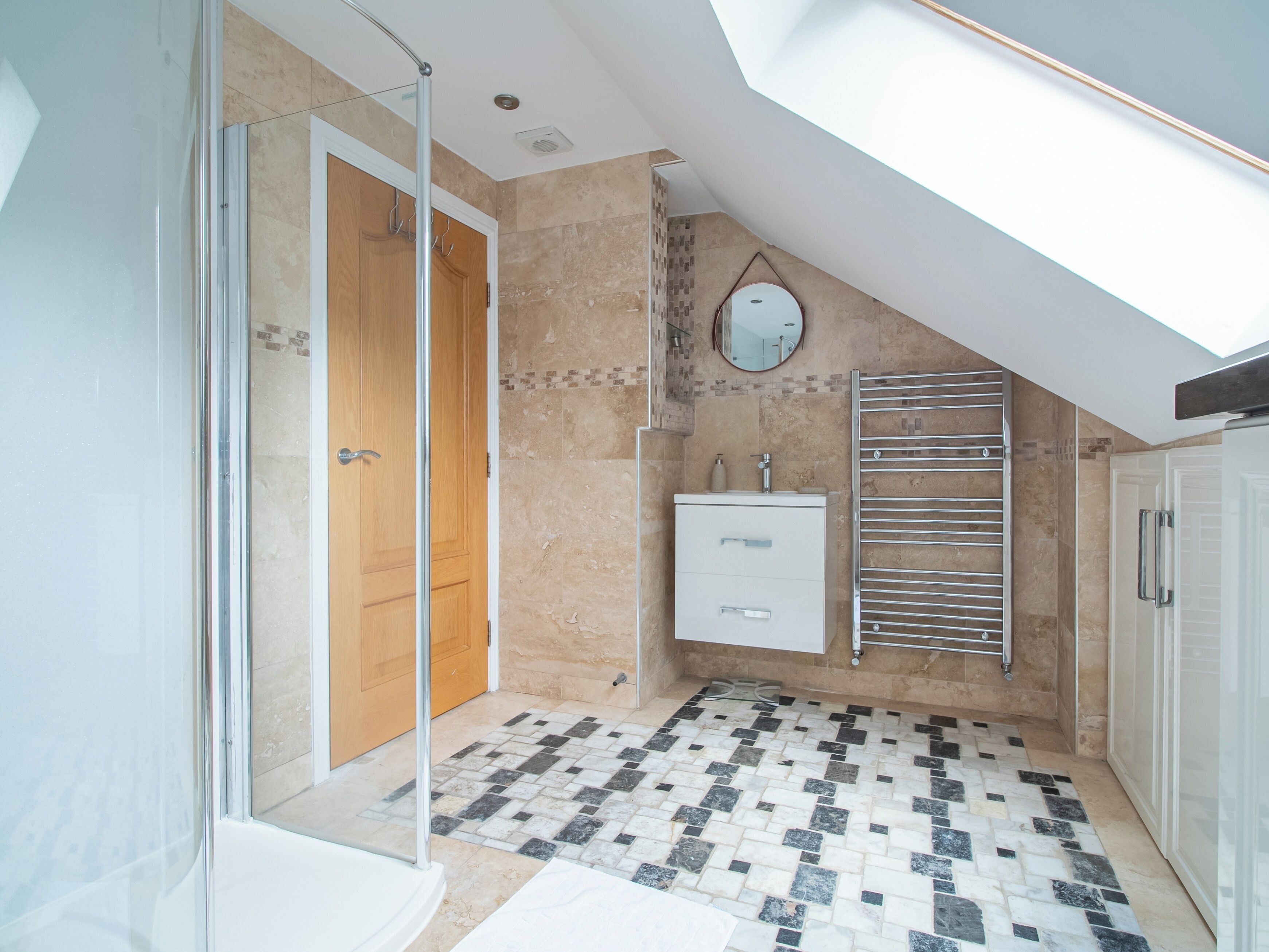 A modern bathroom with a glass shower enclosure, a freestanding bathtub, a vanity with a mirror, and a towel rack.