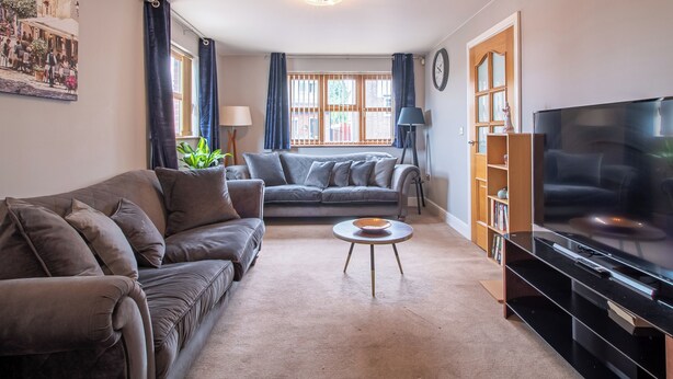 A living room with a sofa, a coffee table, a TV, and a bookshelf. - Luxurious Sheffield Villa With Stunning Views (Sheffield)