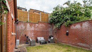 A brick patio with outdoor furniture, a wooden fence, and a tree with white flowers. - Luxurious Sheffield Villa With Stunning Views (Sheffield)