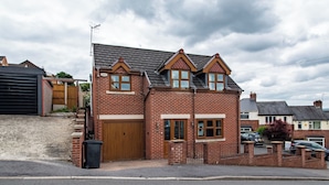 A two-story brick house with a front garage, a small front yard, and a driveway. - Luxurious Sheffield Villa With Stunning Views (Sheffield)