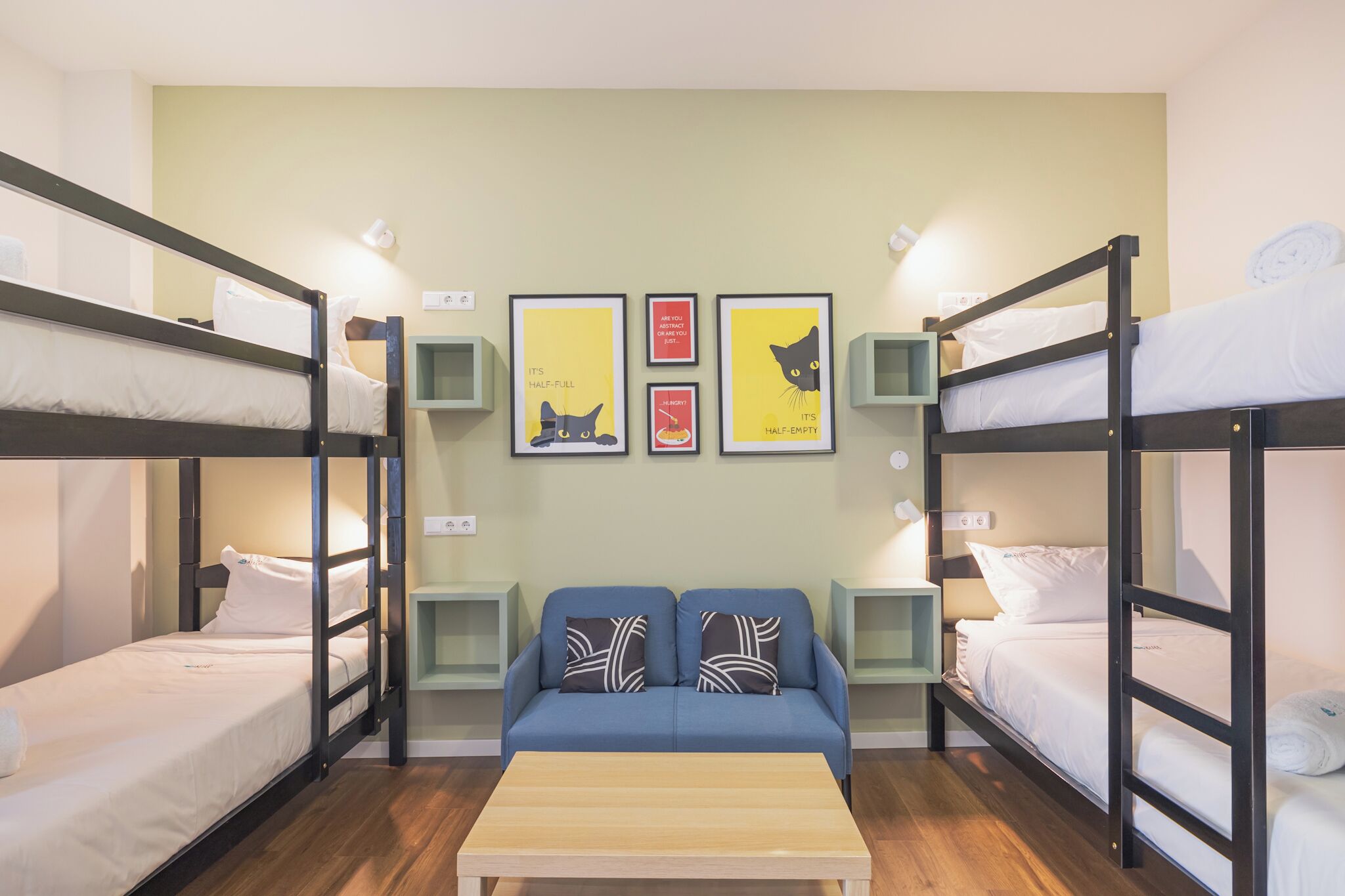 Un dormitorio con literas, un sofá, una mesa y decoración en la pared.