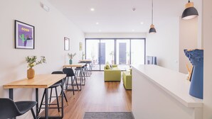 A modern interior with a wooden dining table, black chairs, a green sofa, and a white counter.