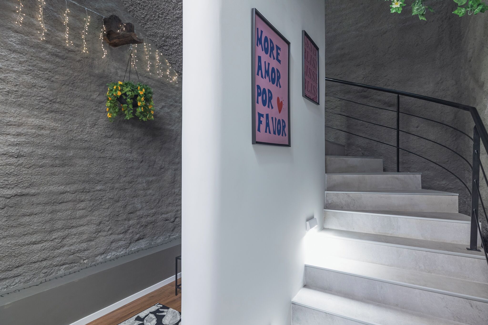 A staircase with a modern design, a textured wall, and decorative lights.